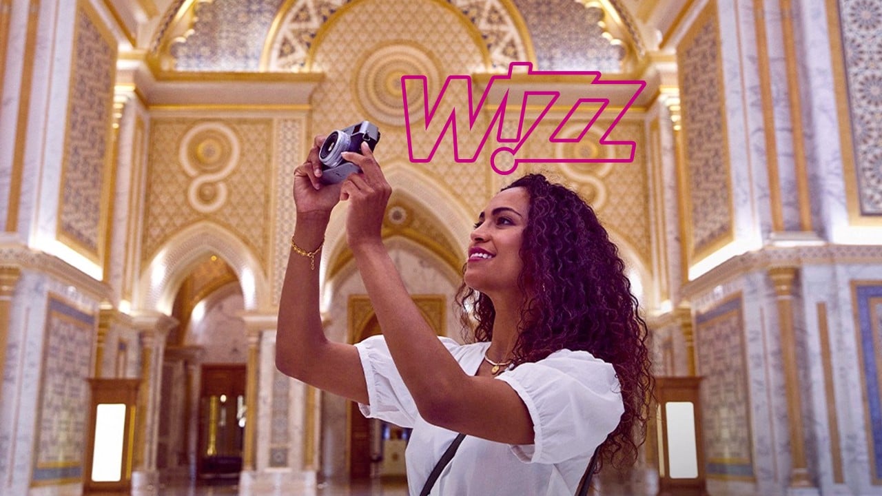 Mulher fotografando museu com logo da Wizz
