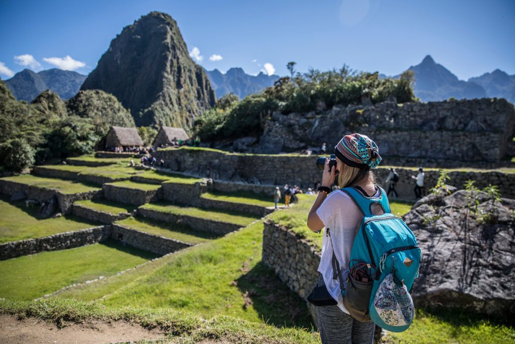 Mulher de mochila tirando foto de local histórico na América Latina