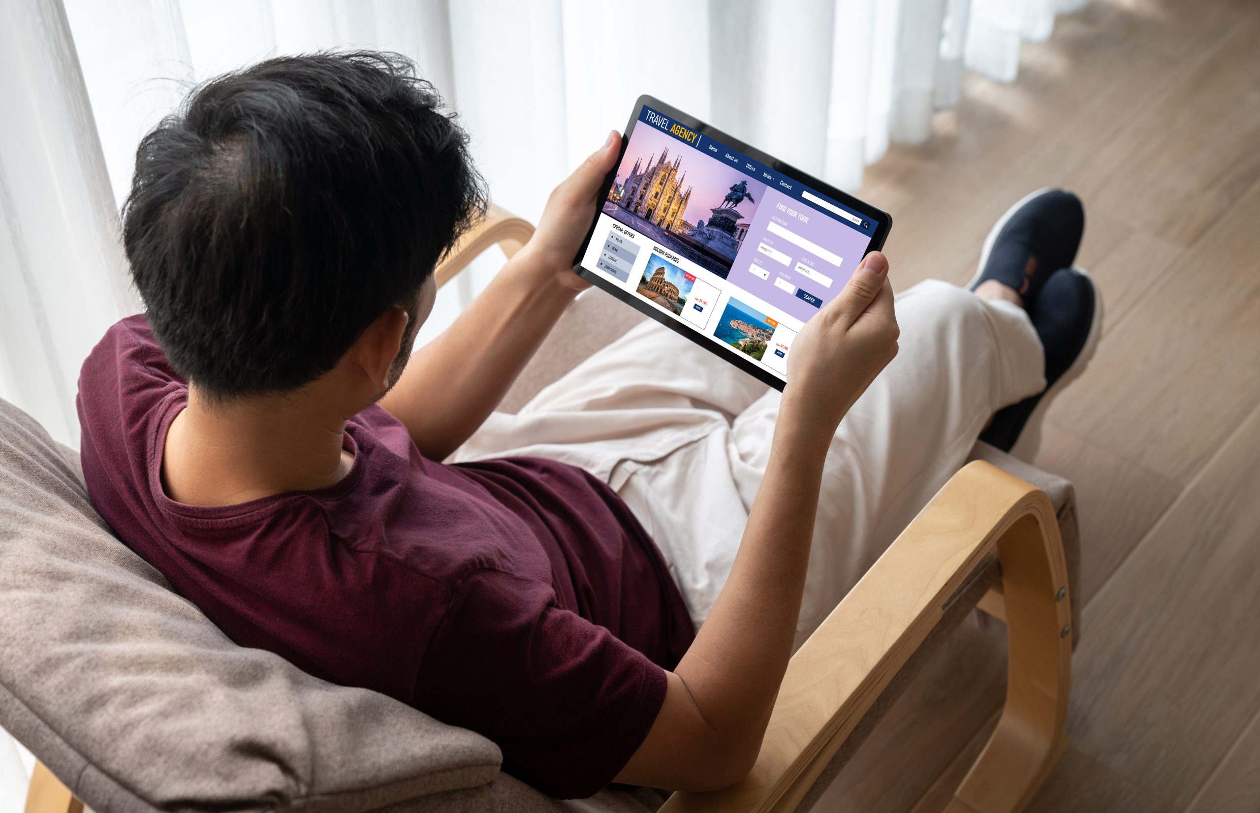 Homem sentado em sofá com tablet na mão